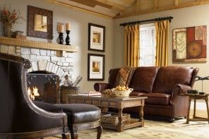 Classic English style interior: hearth, leather furniture with carved wooden basis, coffee table, a lot of pictures, cornices and tapestries