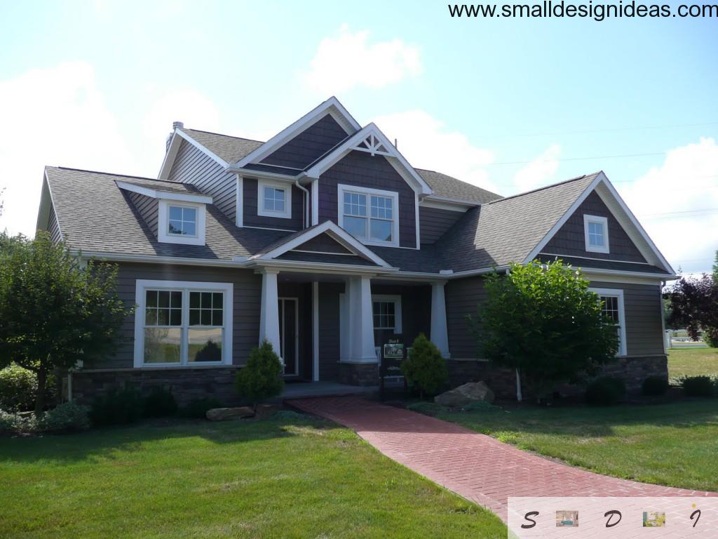 Big house in English style with green decoration, paving slabs and raw rocks