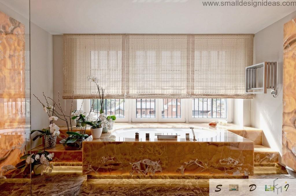 Unique marble trimmed bathtub and Venetian blinds at the huge window in the bathroom