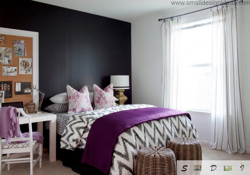 Unique bedroom design in the apartment with black contraatign wall and purple cover on the striped coverlet and two rattan hassocks