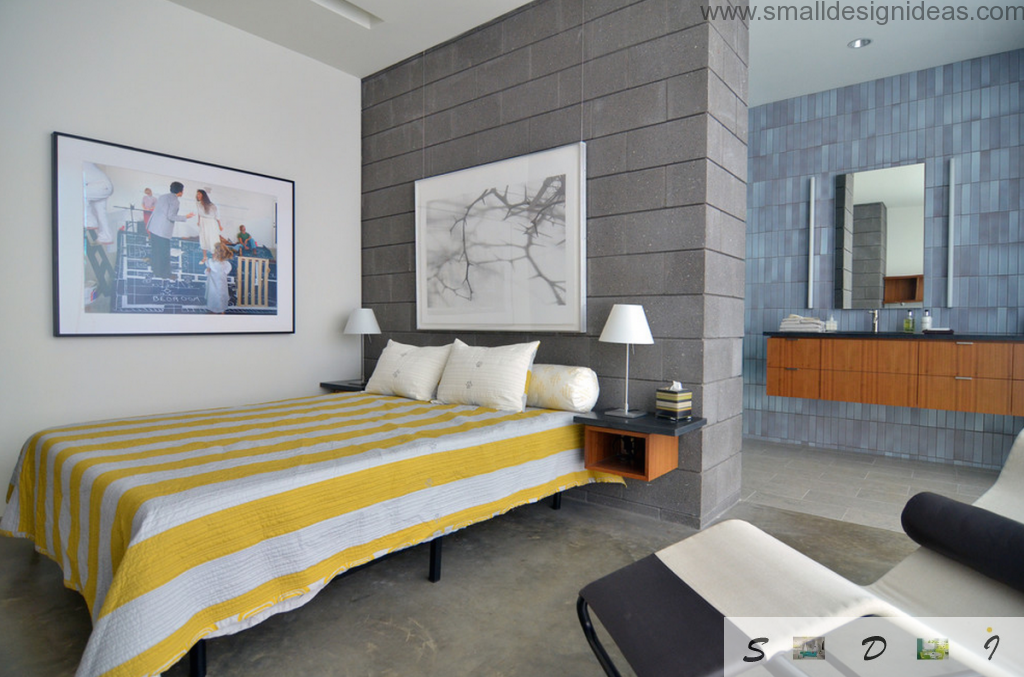 Yellow striped cover on the bed and dark brickwork wall in the hi-tech design of the bedroom