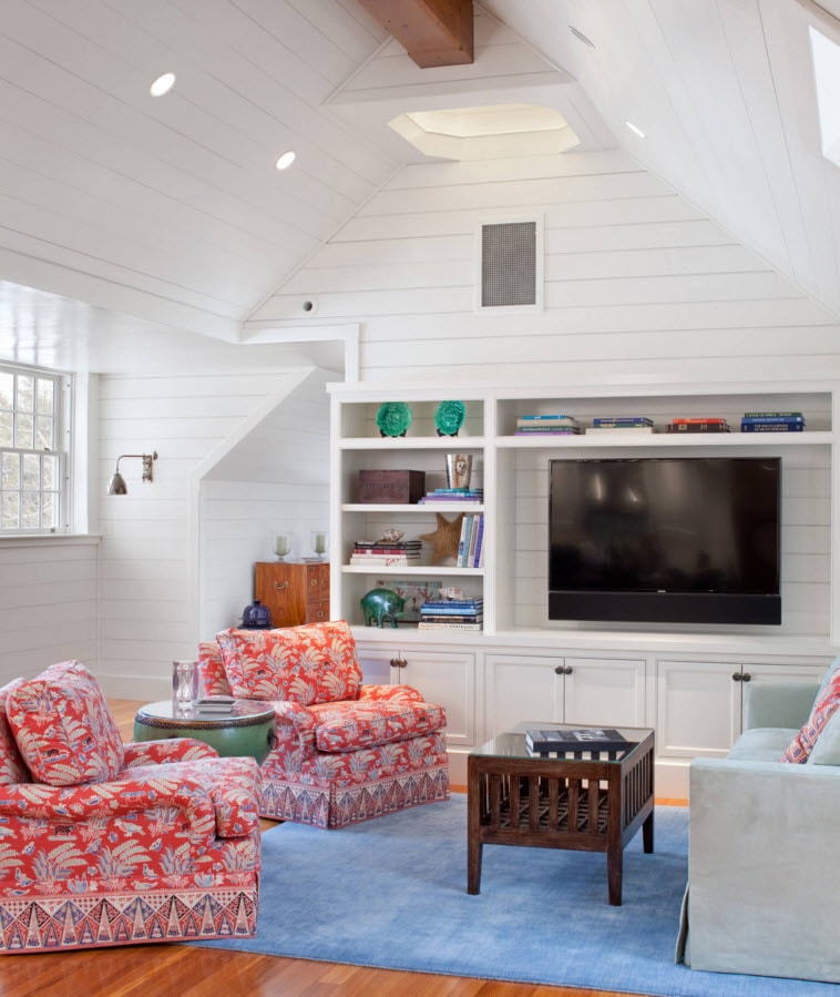 Storage Systems Variety for the Living Room. Red furniture and the sloped ceiling with white wooden panelling and the storage system around the TV area