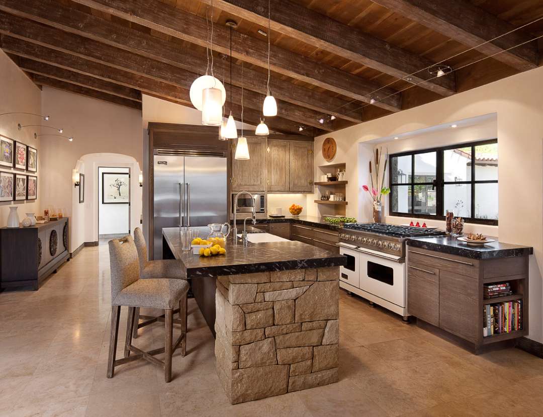 Sloped wooden ceiling with opened beams of the country style looks charming with stone trimmed island in the middle