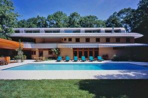 Original Architecture of Private House with In-ground Pool. Azure water and blue sunbeds at the sultry summer day