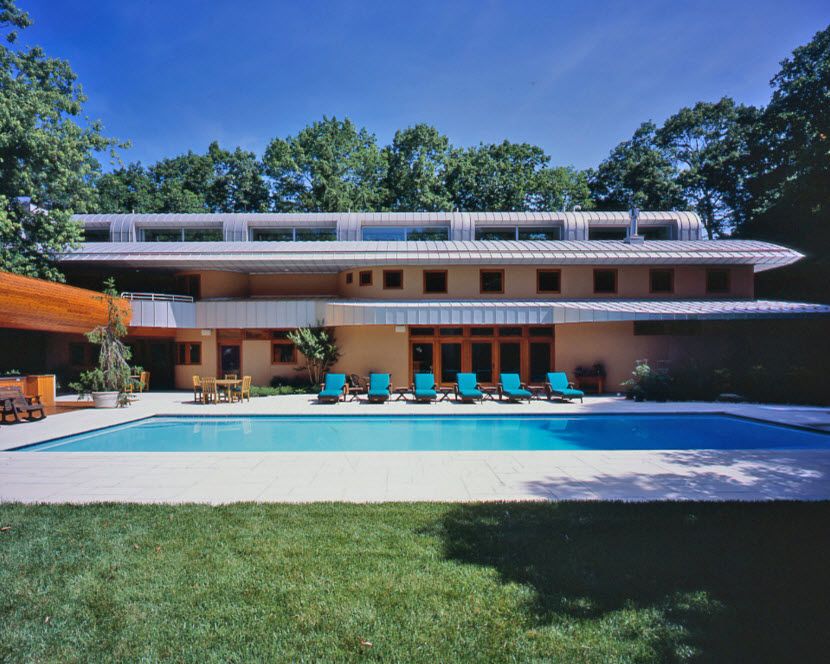 Original Architecture of Private House with In-ground Pool. Azure water and blue sunbeds at the sultry summer day