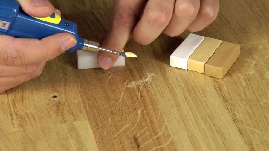 Wax pencil of appropriate color will help you to fix scratches on your laminate