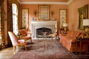 Classic style in the warm peachy living room with the fireplace and golden frames of paints