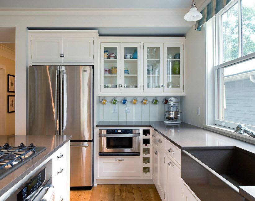 Classic white interior of the kitchen with steel surface of the refrigerator looks nice