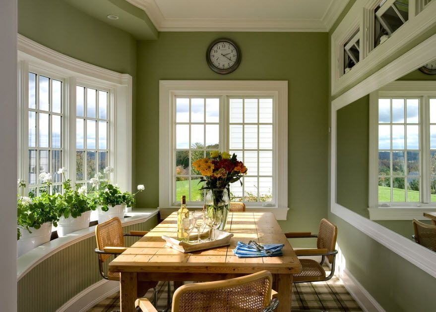 Классическая расслабляющая атмосфера в оливковой столовой частного дома с решетчатыми окнами и большим светлым деревянным столом.