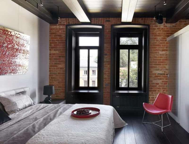 Industrial styled bedroom with brickwork walls and dark wooden window panes