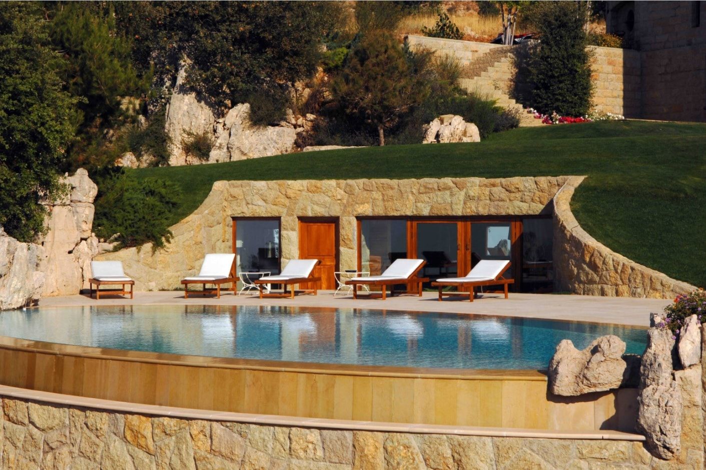 House Built Into Hill or Underground Houses. Poolside lounge zone surrounded by nature