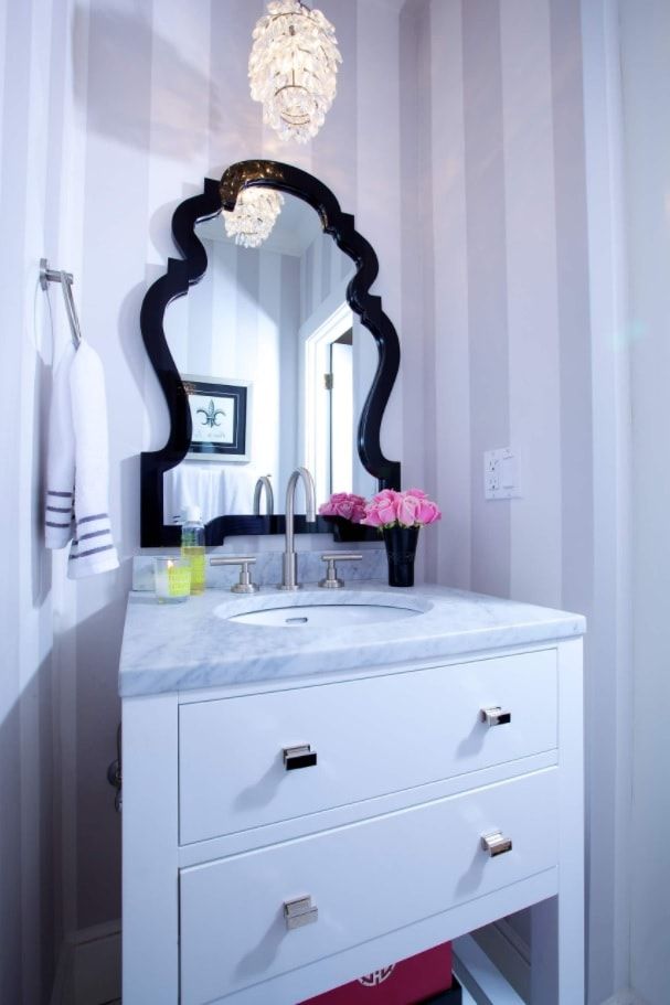 Black figured mirror in the bathroom with wallpapered walls