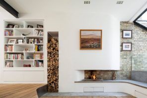 White matte living room interior in minimalistic Scandi style with hole for firewood in the wall near fireplace