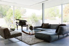 Glass coffee table next to the leather upholstered angular sofa