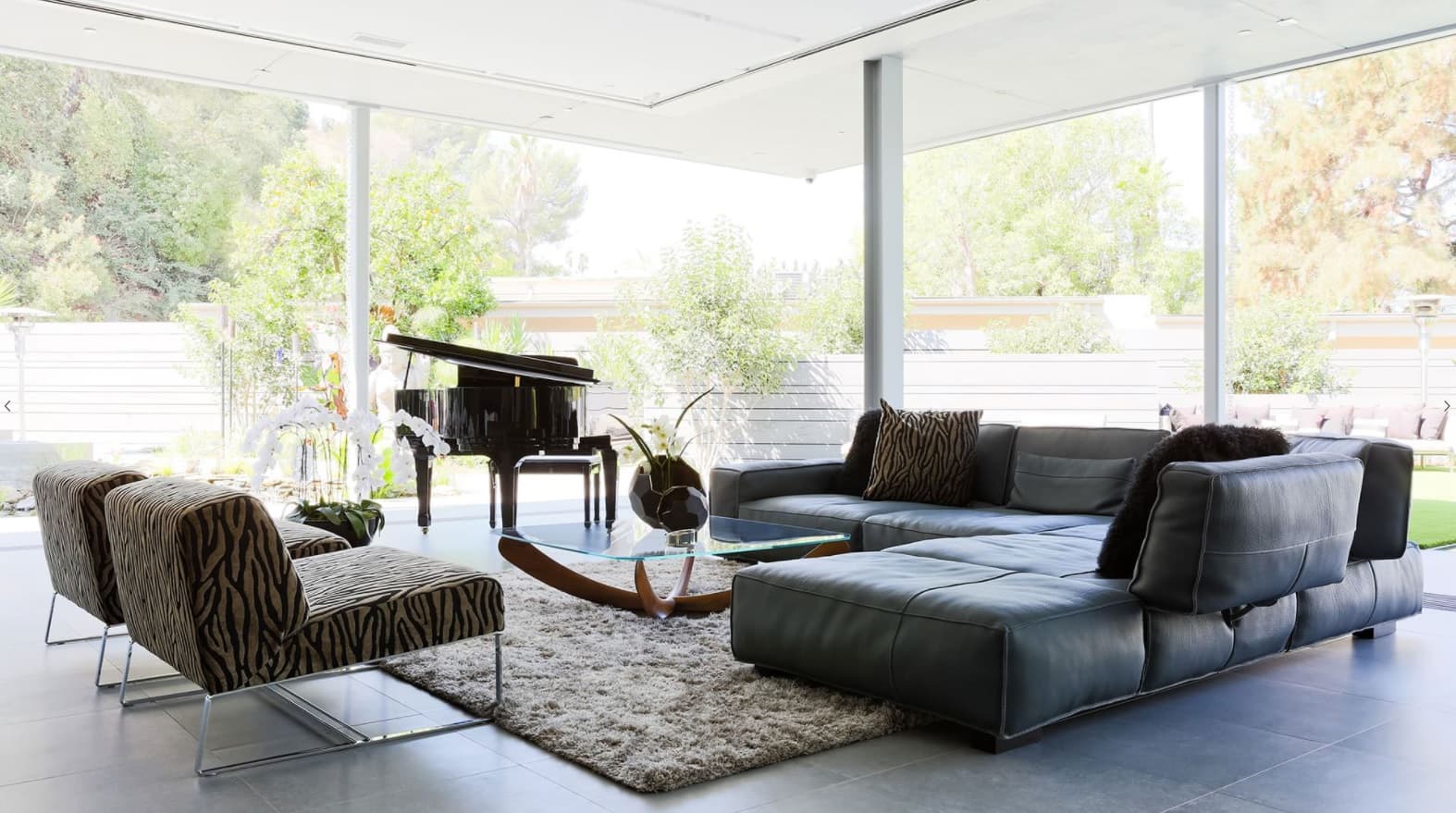 Glass coffee table next to the leather upholstered angular sofa