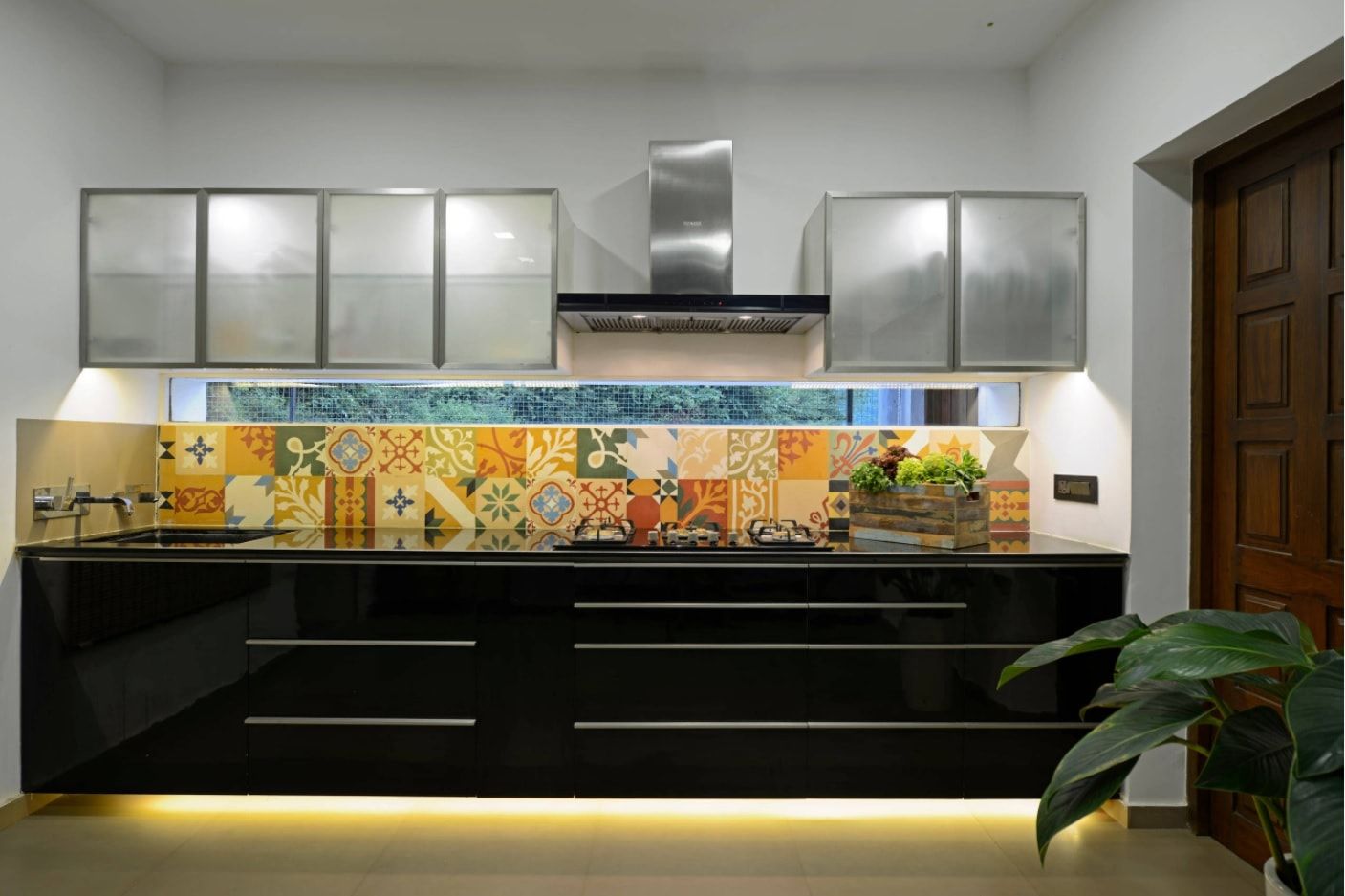 Modern kitchen with dark low tier and LED lighting of the floor, painted Moroccan tiled splashback and silver coated high tier of the furniture set