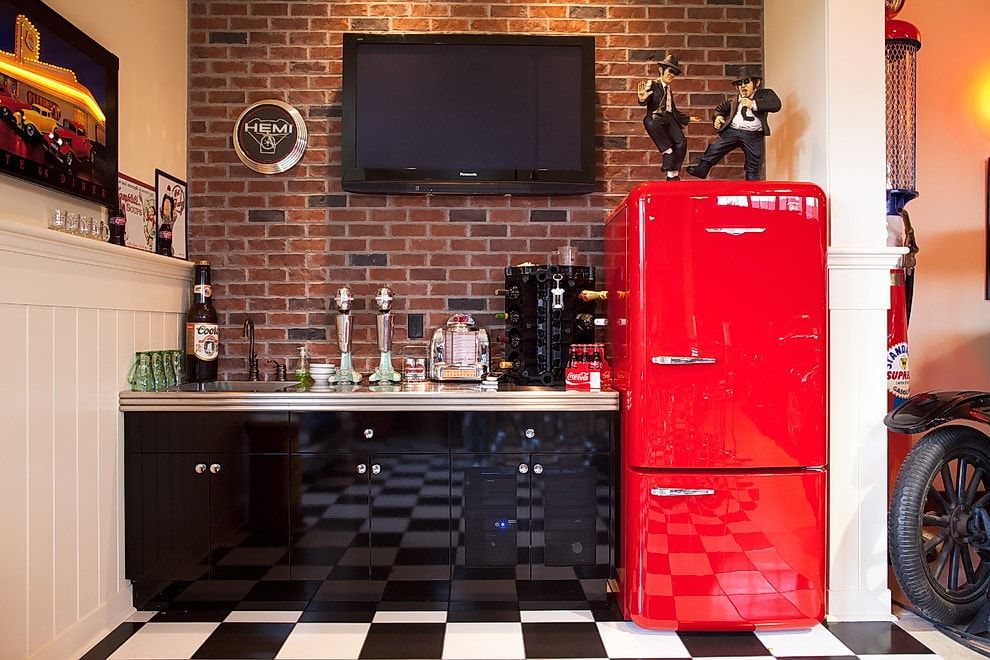 Red accentual spot of the fridge in the Industrial styled kitchen with brickwork