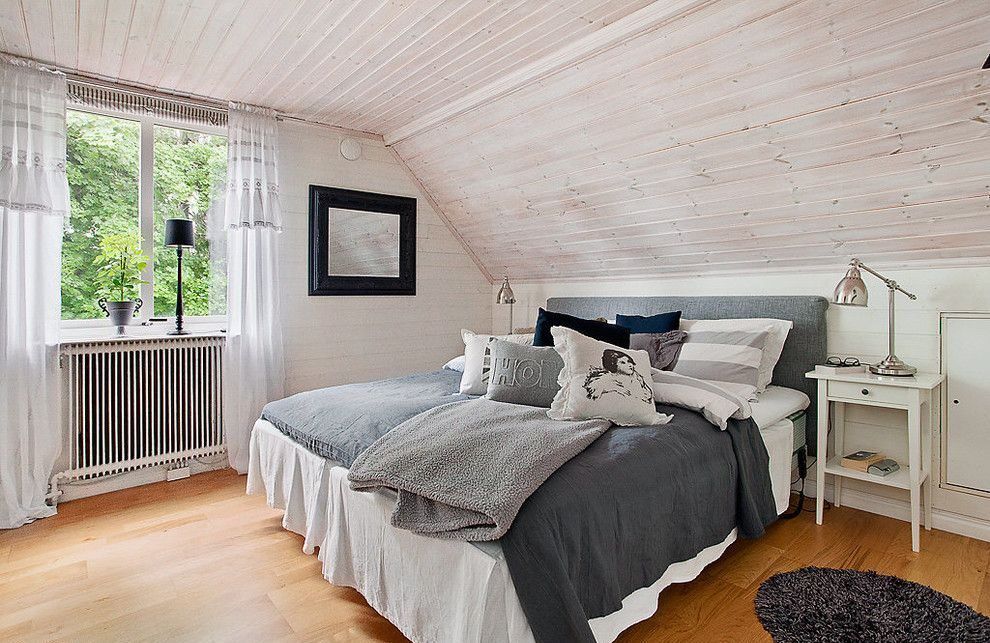 Light wooden planked attic bedroom with royal sized bed