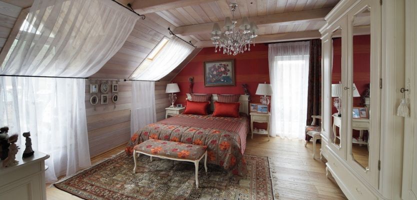 Crystal chandelier and red accent wall for the attic bedroom with wooden trimmed walls