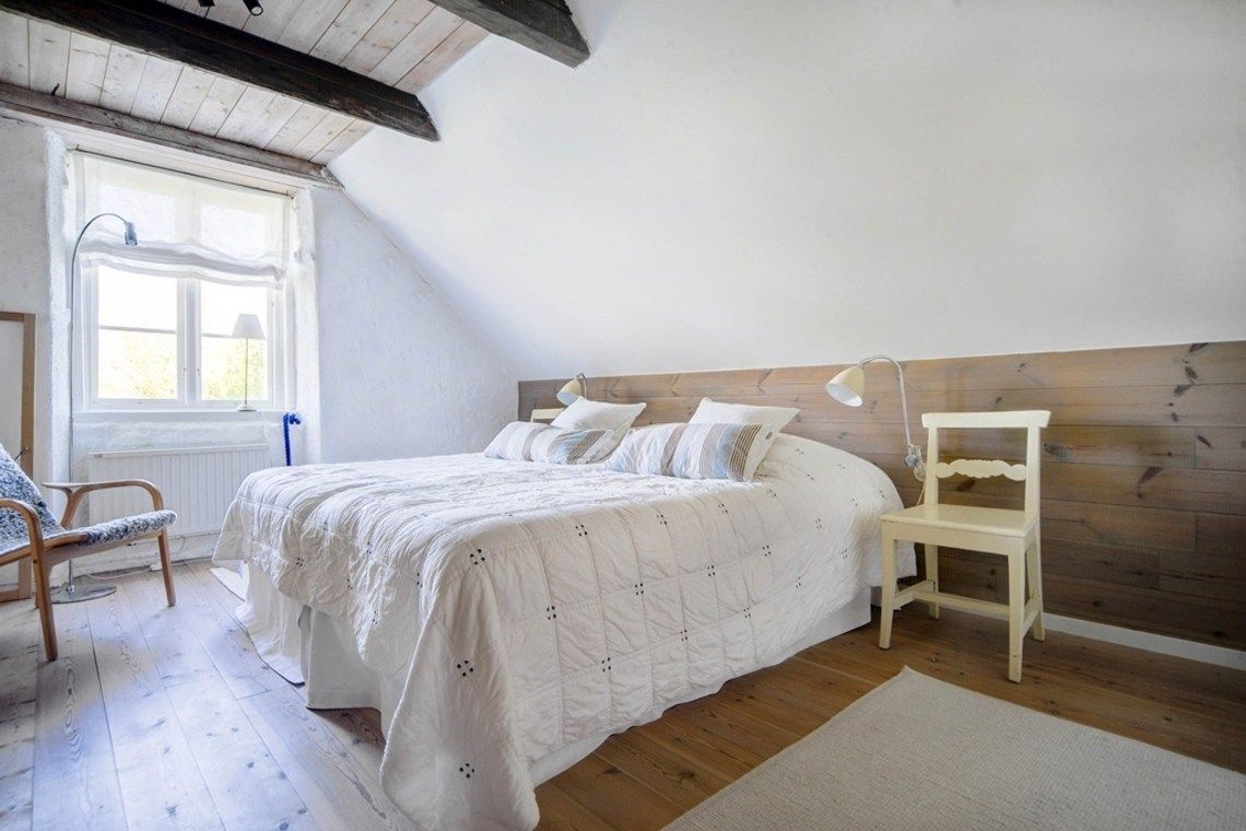 White bedroom with large window and dark wooden ceiling beams