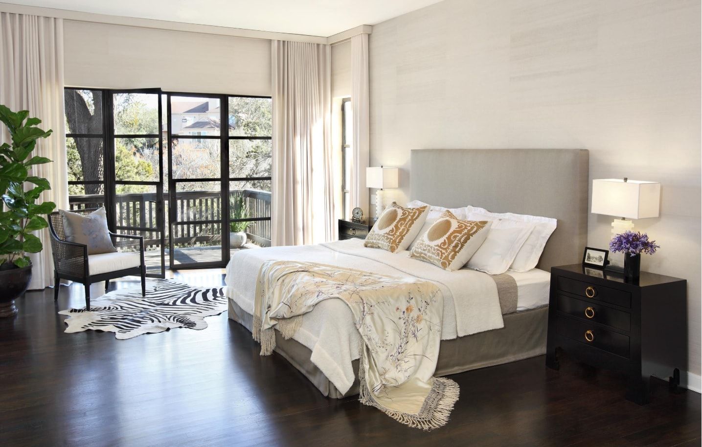 Casual styled bedroom with large bed, soft headboard and dark wood floor