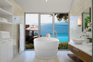 Acrylic Bathtub as the Highlight of Modern Bathroom Interior. Round shaped font at the seashore private house