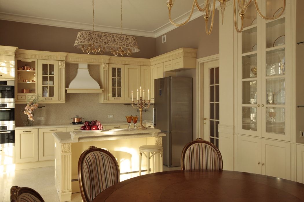 Italian Dining Room & Kitchen Combined in One Space. Dining zone with round wooden table and overall ivory color set of the room