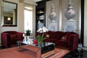 Greek Interior Design Style: Antiquity in Your Home. Mirroring coffee table and deep red upholstered furniture for Classic living room