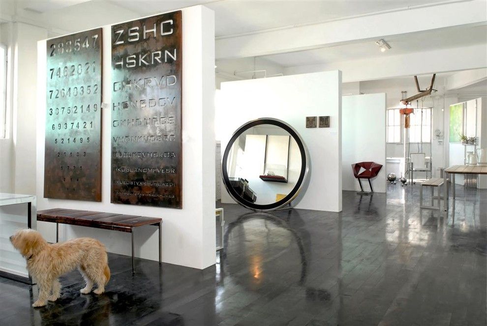 Large round mirror with black frame in the wall separated zone of the large Industrial styled apartment's interior