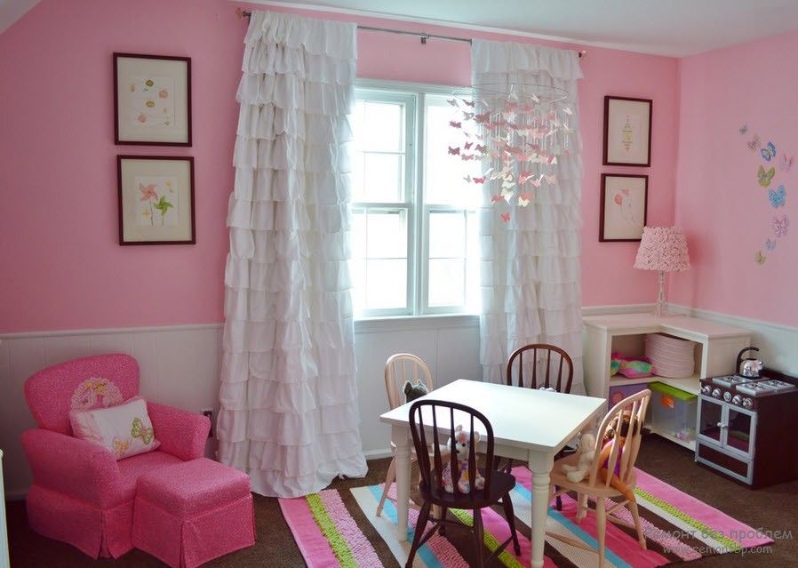 Curtains in the Interior of the Children’s Room. White tulle in the window of the pink painted room with striped rug