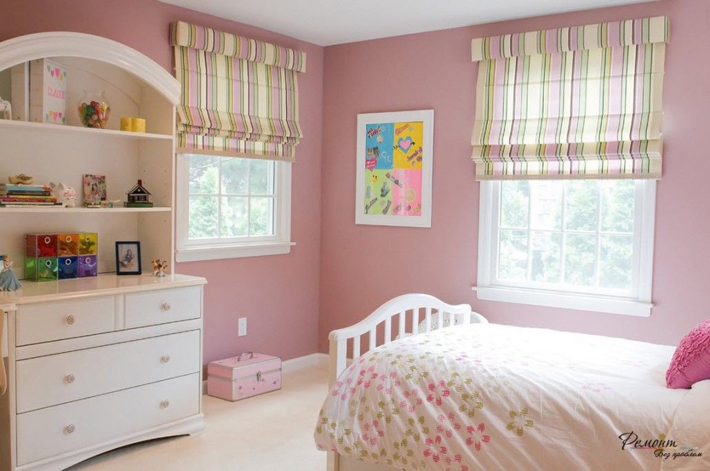 Dark pink wall color and pastel Roman blinds in the children's room with white furniture