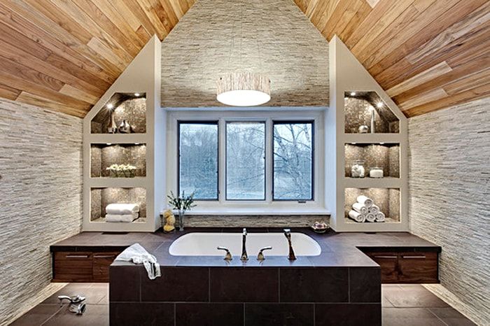 Royal attic bathroom design with large window and central placement of bathtub with many controls and taps