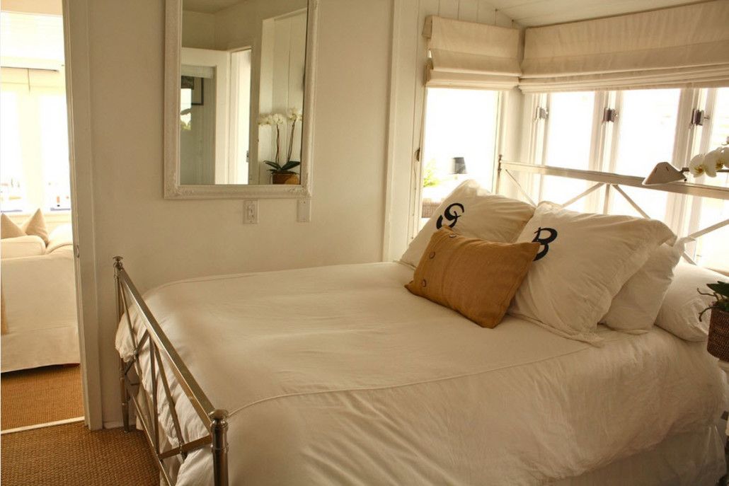 Small bedroom with large bed, windows and mirror