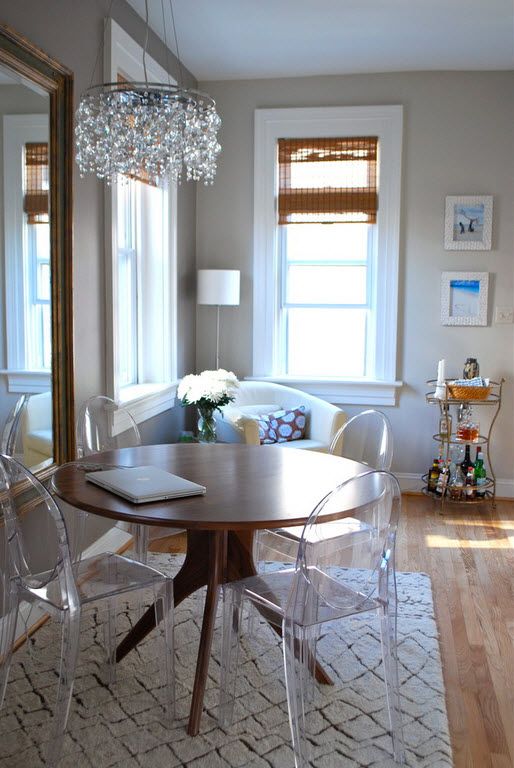 Round wooden table and transparent plexiglass chairs for small dining zone