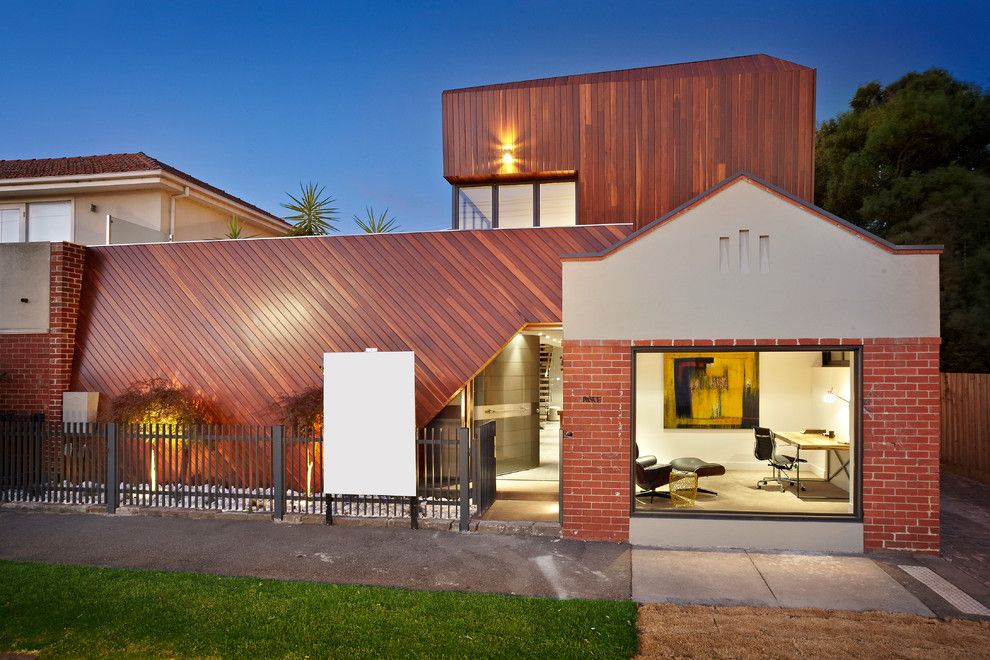 Unusual designed house with reddish tint of the wooden facades
