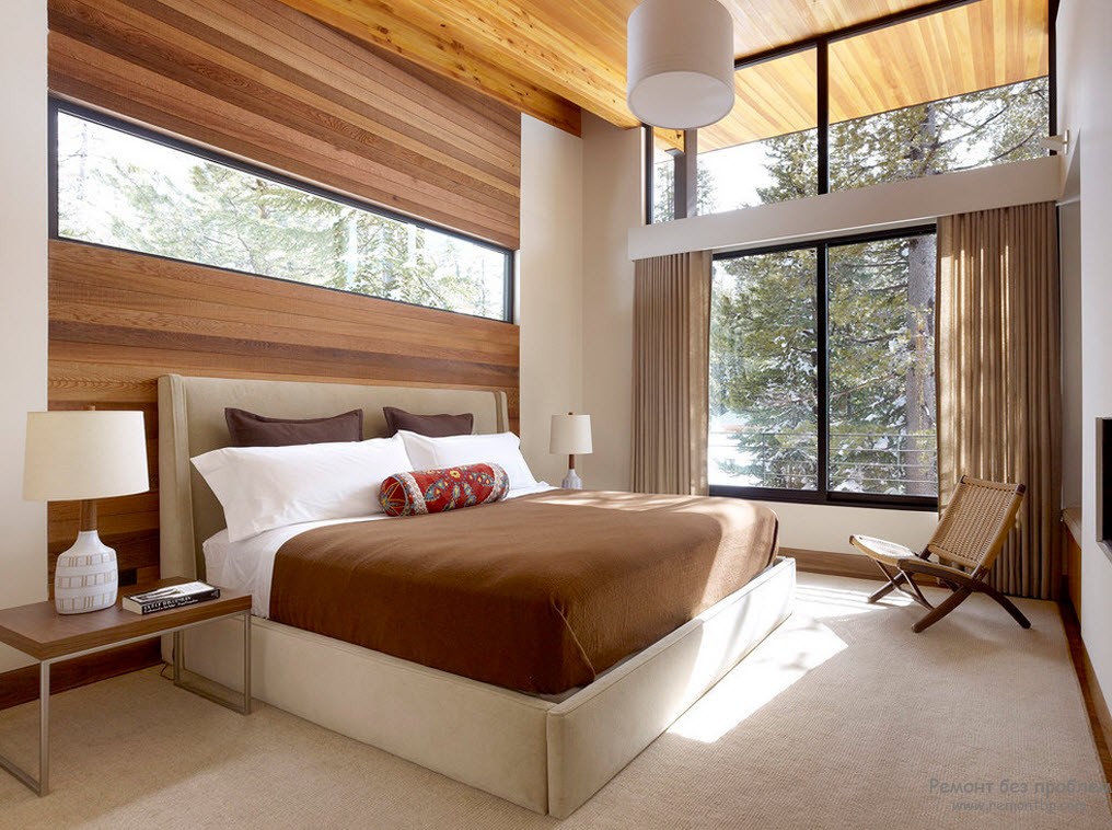Window Design in the Bedroom for Ultimate Coziness and Comfort. Modern interior of the forest cottage with panoramic windows and wooden trimming