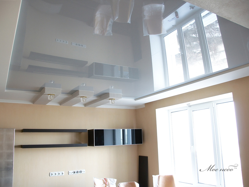 Suspended glossy ceiling for the modern designed kitchen with light wooden furniture