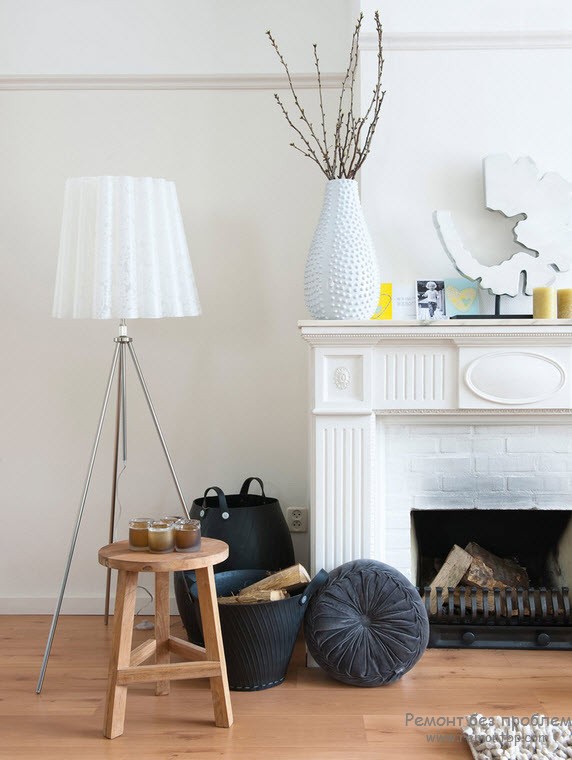 White vase and dofferent elements to adorn the mantelshelf of classic fireplace