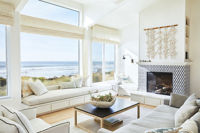 Cozy living room if the beach house with high ceiling and panoramic windows