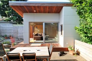 Sliding Glass Doors and Glass Wall Panels in Modern Commercial Interiors. Outside view if the backyard of the cottage with wooden platform outside the building