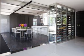 The Interior Design Guide For Styling a Gentleman’s Elegant Man Cave. Kitchen zone on pedestal and glass casing for the wine shelving