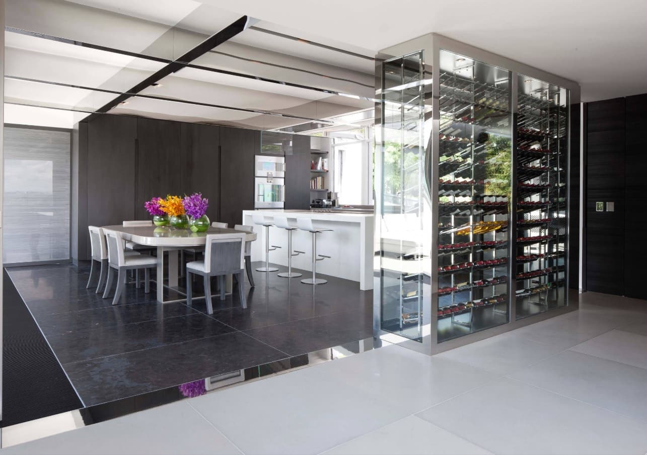 The Interior Design Guide For Styling a Gentleman’s Elegant Man Cave. Kitchen zone on pedestal and glass casing for the wine shelving