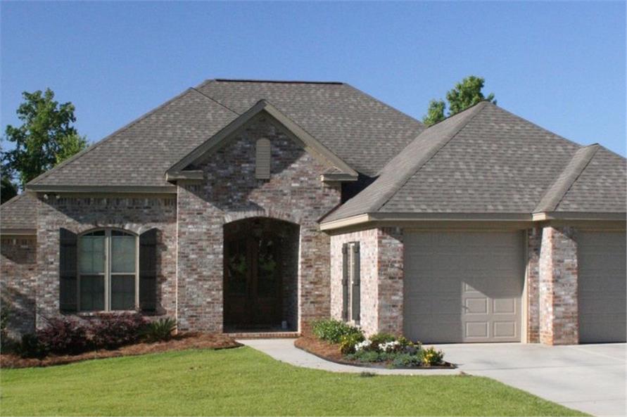 Acadian styled house with stone exterior and dark wooden entrance door