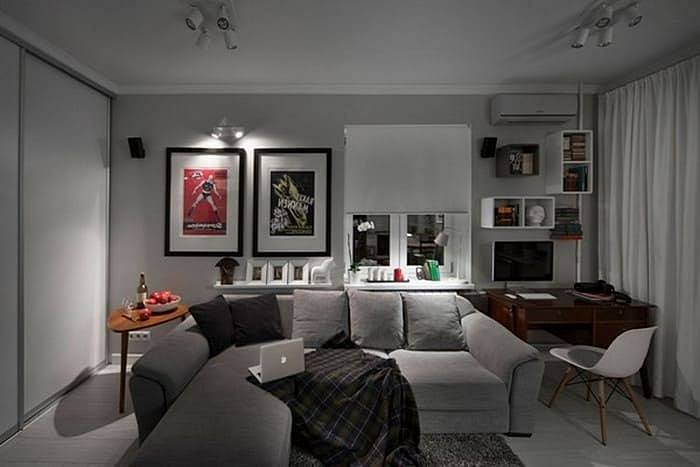 Dark living room interior with predominance of gray and abundance of artificial lighting