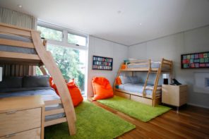 Bunk Bed as an Option to Enhance the Interior Functionality. Playground for children with green fluffy rugs and orange bean bags