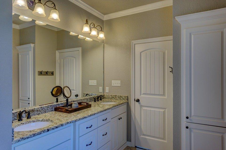 Classic designed bathroom with dark gray painted wall, large mirror and vanity with marble top