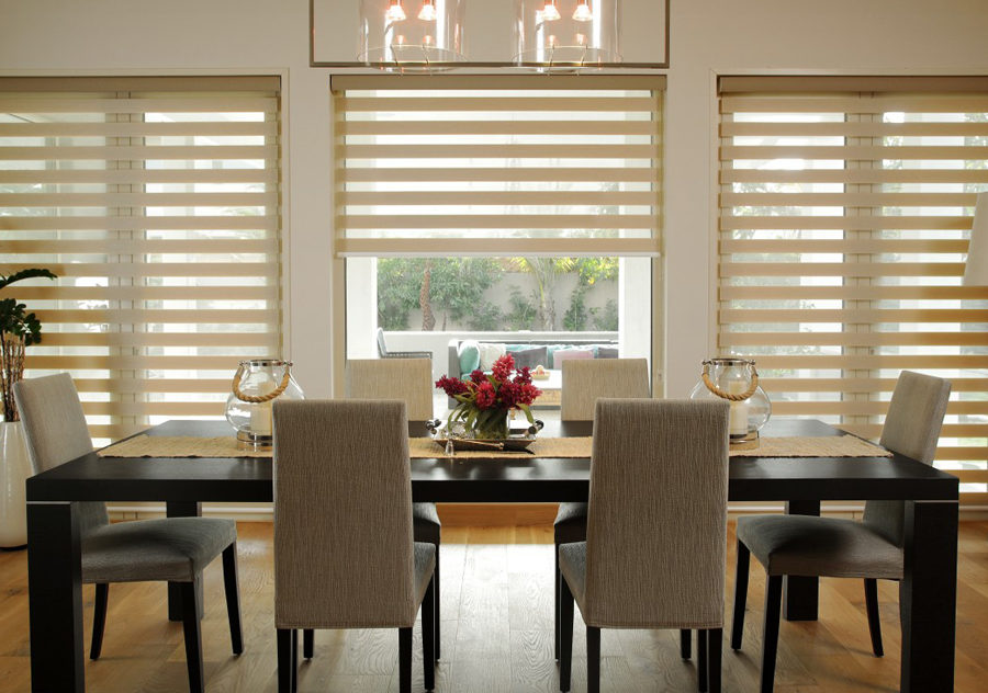 Dining room with black table and possibility of total blackout by mean of creamy colored roller blinds