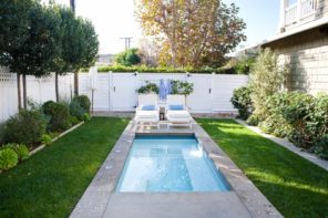 8 Steps to Take to Prepare Your Pool for the Summer. Concrete brimmed pool with white sunbeds near