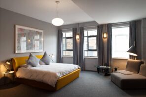 How to Breathe New Life into Your Home’s Interior Design. Great example of urban styled bedroom with brickwork wall and full of natural light despite the gray carpeting and paint