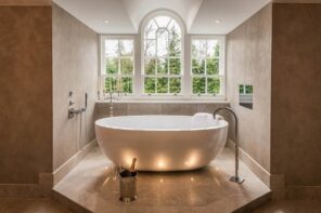 Multi-Level Lighting as Effective Way to Set Accents and Emphasize Interior. Arched window and the eggshell bathtub in the limelight of the spacious bathroom